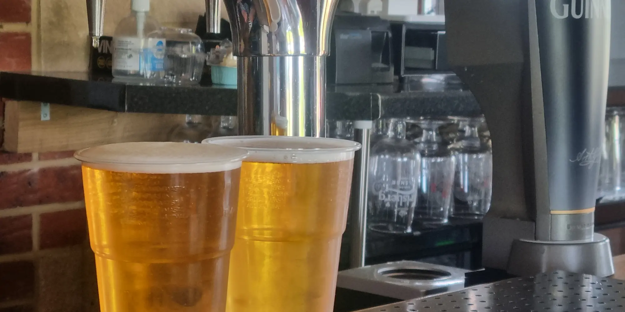 Two pints of beer on the bar below the hand pumps