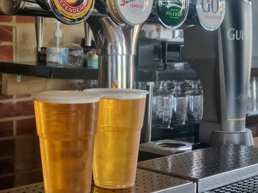 Two pints of beer on the bar below the hand pumps