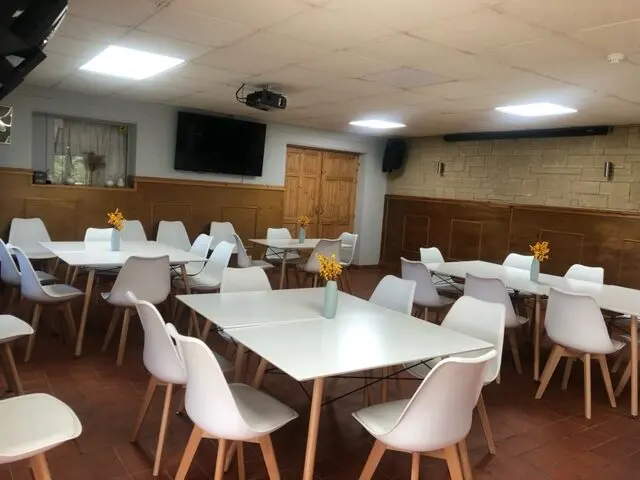 Tables and chairs set out in the cafe with a TV on the wall