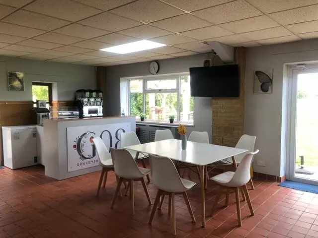 Tables and chairs inside Gouldy08 cafe with the counter and G08 sign
